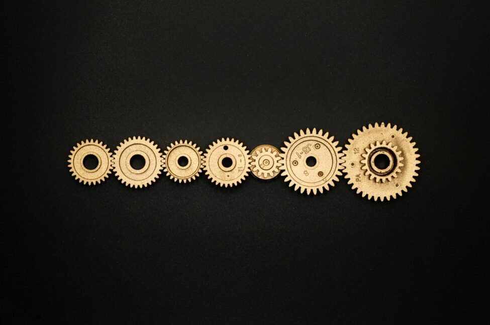 seven cogs in a line, connected with each other | How Physicians Can Overcome Financial Perfectionism